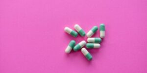 white and blue medication pill on pink textile
